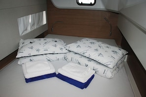 Un lit avec des coussins à motifs, une tête de lit en bois et une fenêtre.