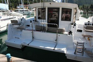 Ein weißes Boot liegt in einer Marina festgemacht, mit einer Kabine, einem kleinen Deck und einer Leiter.