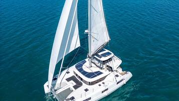 Een zeilboot met een witte romp en meerdere zeilen, drijvend op kalm blauw water.