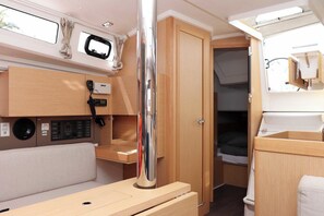 A compact RV interior with a kitchenette, a control panel, a bed, and a door leading to another room. - Sun-Kissed Sailing Adventure in Zadar, Croatia (Biograd na moru)