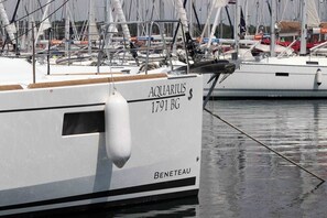 A boat named 'Aquarius 1791 BG' docked at a marina with other boats in the background.