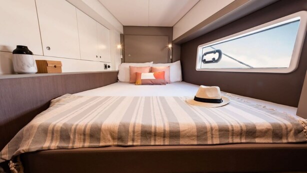 A compact bedroom with a bed, pillows, a hat, and a window with a view. - Caribbean Bliss: Sun-Soaked Sailing Adventure from San Martín, Anse Marcel (Anse Marcel)
