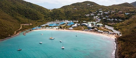 An aerial view of a coastal area with a beach, boats, and buildings.