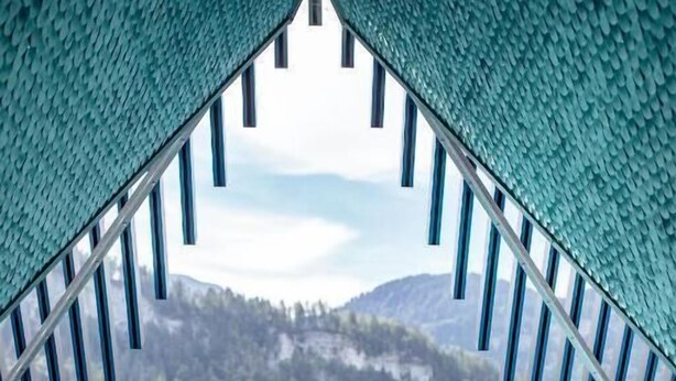 Una piscina con vistas a un paisaje montañoso, rodeada por una zona cubierta con barandilla de metal.