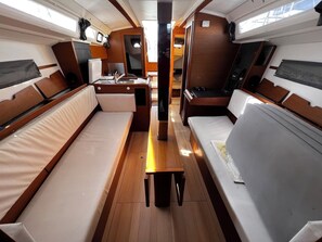 A compact interior with a central table, two sofas, a small desk, and a window. - Sun-Kissed Sailing Adventure in Zadar, Croatia (Bibinje)