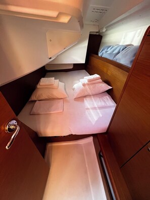 A compact cabin with a bunk bed, a small table, and a door with a handle. - Sun-Kissed Sailing Adventure in Zadar, Croatia (Bibinje)
