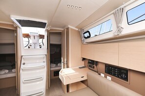 Ett kompakt inre utrymme i husbilen med ett litet kök, ett litet bord, en säng och ett fönster med gardiner.