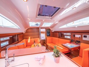 Interieur van een jacht met een glazen dak, zitgedeeltes, een tafel met een kaart en een bedieningspaneel.