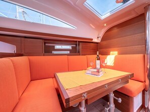 A yacht interior with a wooden table, orange cushioned seating, and a skylight. - Sun-Kissed Sailing Adventure in Split, Croatia (Split)