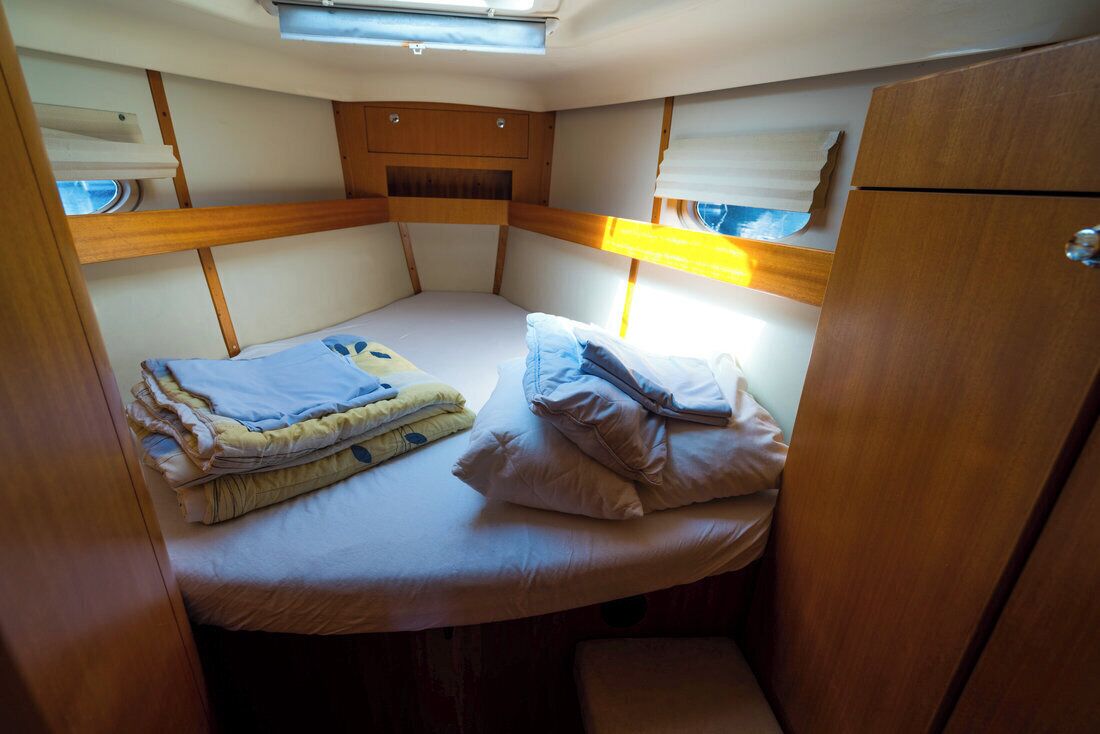 Una cabaña compacta y bien iluminada con una cama litera, armarios de madera y un tragaluz.