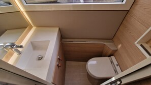 A compact bathroom with a sink, toilet, and shower area.