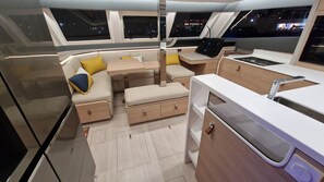 L’intérieur d’un bateau, comprenant un coin repas, des sièges et un panneau de commande.