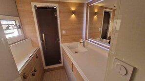 A compact bathroom with a dark door, a white sink, a mirror, and a window.