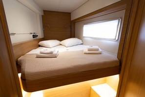 A bunk bed with a headboard, a window, and a bedside table with a lamp.