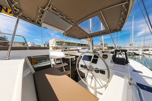 A boat's deck with a steering wheel, control panel, and seating area. - Sun-kissed Sailing Adventure in Split-Dalmatia, Croatia (Trogir)