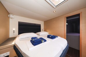 Habitació d'hotel amb un llit, taules de nit, un capçal i un ventilador de sostre, i una porta que dona a un bany.