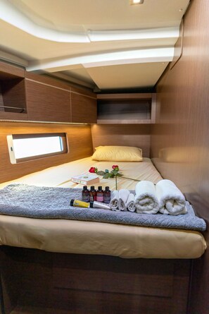 A compact, well-lit room with a bed, a small window, and a bedside table with toiletries.