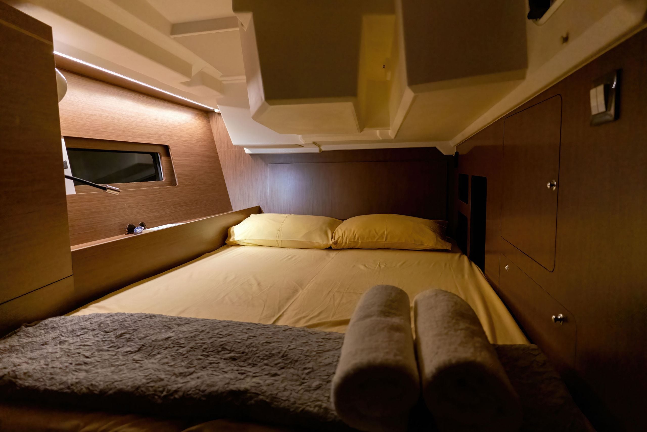 Habitació compacta amb un llit, una finestra petita i una prestatgeria integrada.