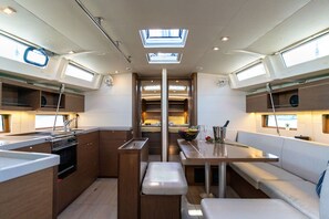 A compact kitchen with a central island, a dining area with a bench, and a small seating area with a table and cushions.