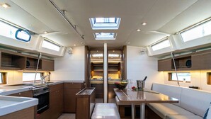 Une cuisine compacte dotée d’un îlot central, d’un coin repas avec un banc et d’un petit espace détente avec une table et des coussins.