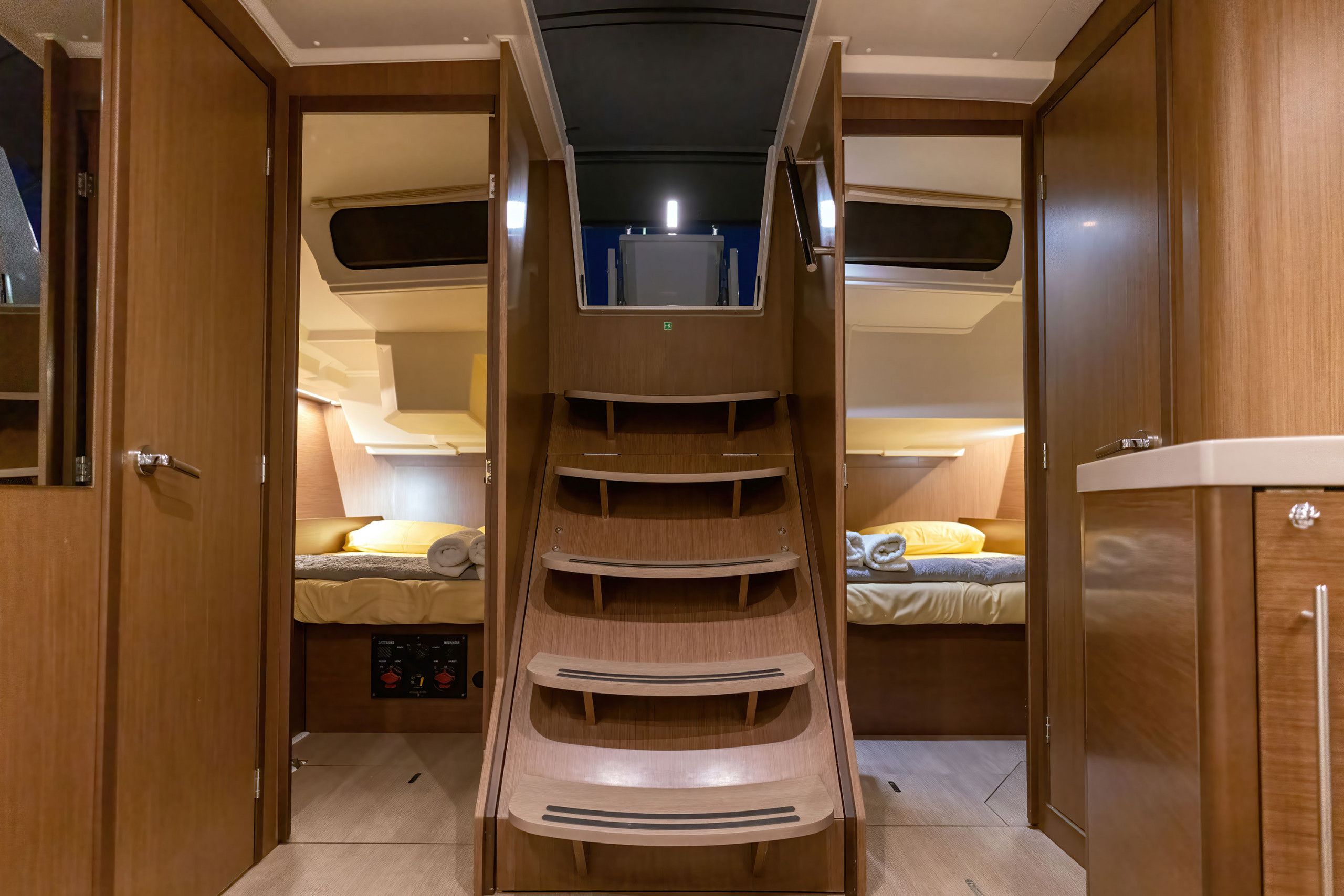 Een compact interieur met een centrale trap, een bed met gele beddengoed, en een bedieningspaneel.