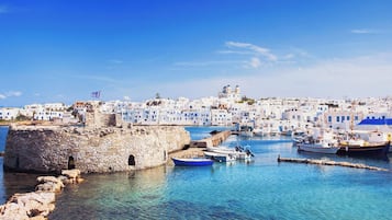 Un pueblo costero con edificios de piedra, cielo azul despejado y barcos en el puerto.