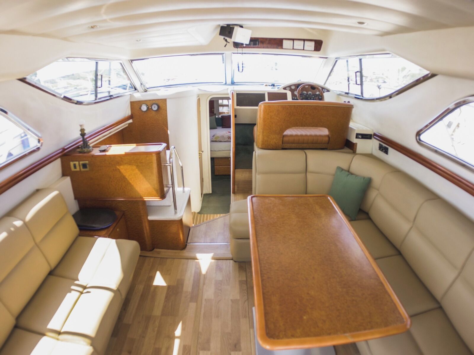 Interior de un barco con comedor, asientos y panel de control.