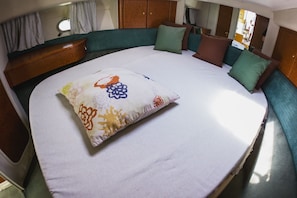 Ein Bett mit einem blumigen Kopfkissen, einem grün gepolsterten Kopfteil und einem Holzschrank.