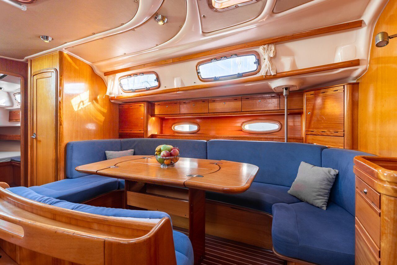 Un interior compacto y bien iluminado con una mesa de madera, asientos acolchados en azul y armarios empotrados.