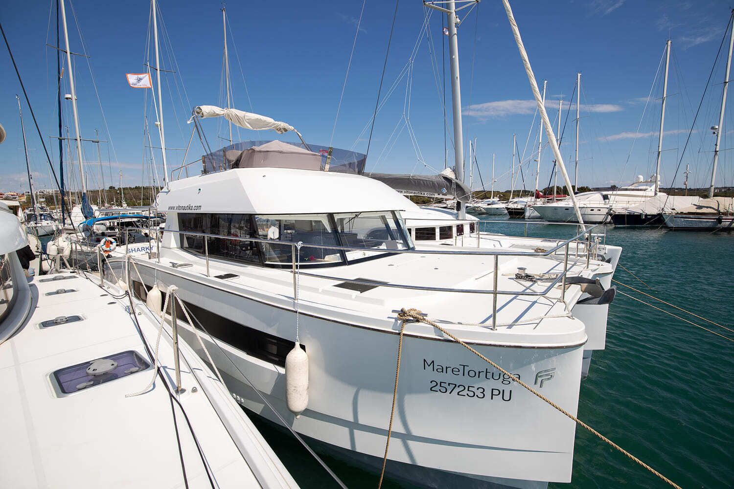 Ein Yachthafen mit mehreren Segelbooten im Hafen, darunter ein Boot namens 'Marelontuga 257253 PU'.
