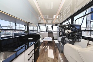 A boat interior with a kitchen area, seating, and a steering wheel. - Sibenik Sun and Beach Sailing Extravaganza (Tribunj)