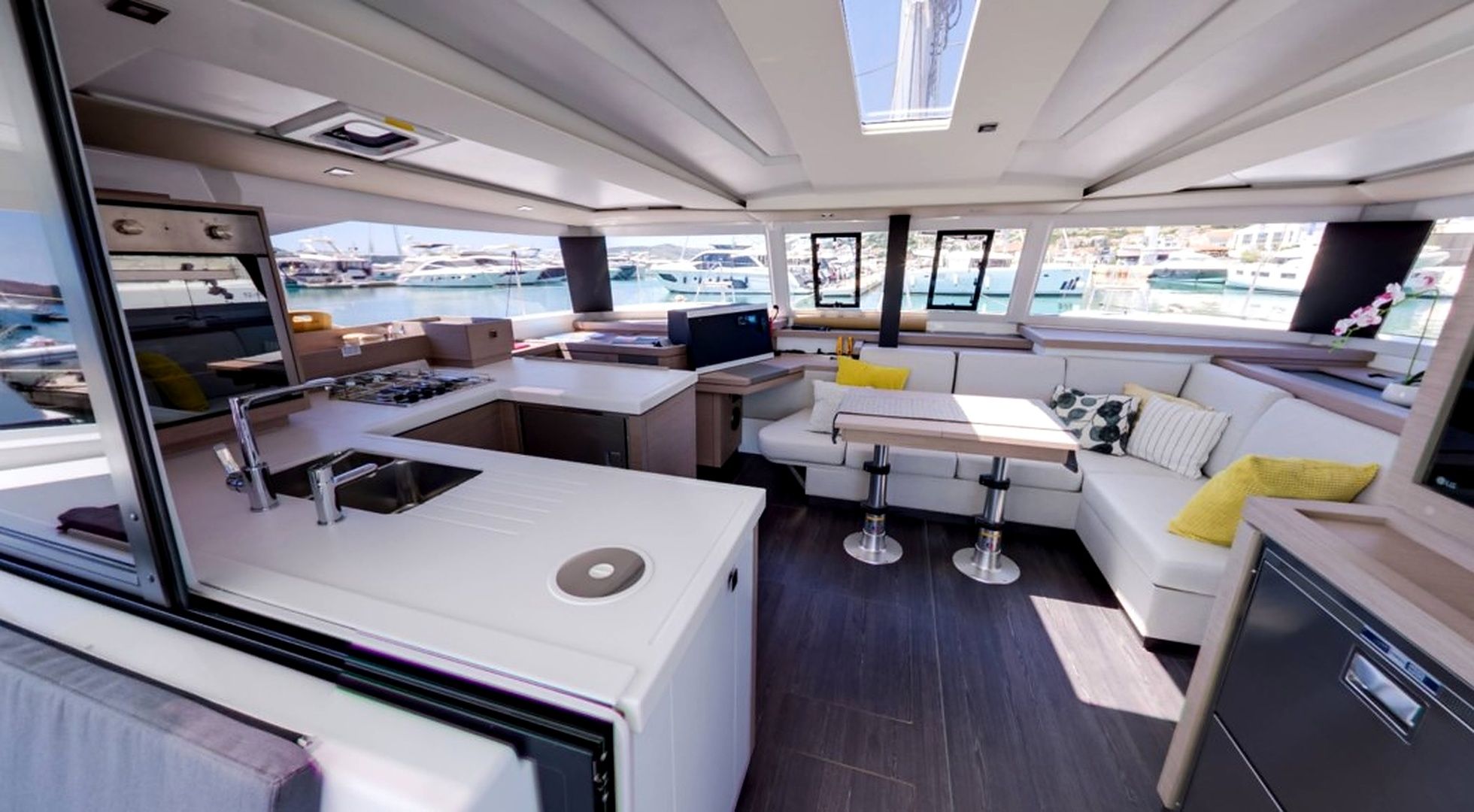A modern yacht interior with a kitchen, dining area, and seating.