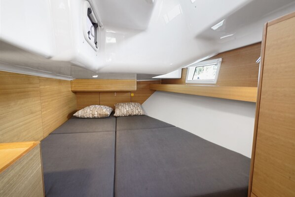 A compact, modern interior with a bed, wooden paneling, and a small window.