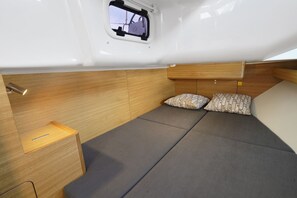Ein kleines, gemütliches Interieur mit einem Bett, einem kleinen Fenster und einem Holzschrank.
