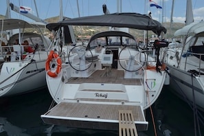 Ein Yachthafen mit einem weißen Boot namens 'Tokaj', das an einem Steg liegt. Es verfügt über ein überdachtes Deck, ein Steuerrad und einen Rettungsring.