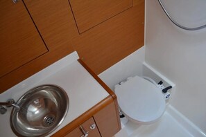 Un baño con un lavamanos blanco, un inodoro y armarios de madera.