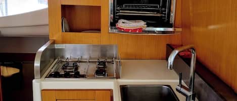 A compact kitchen with a built-in oven, a gas stove, and a double sink.