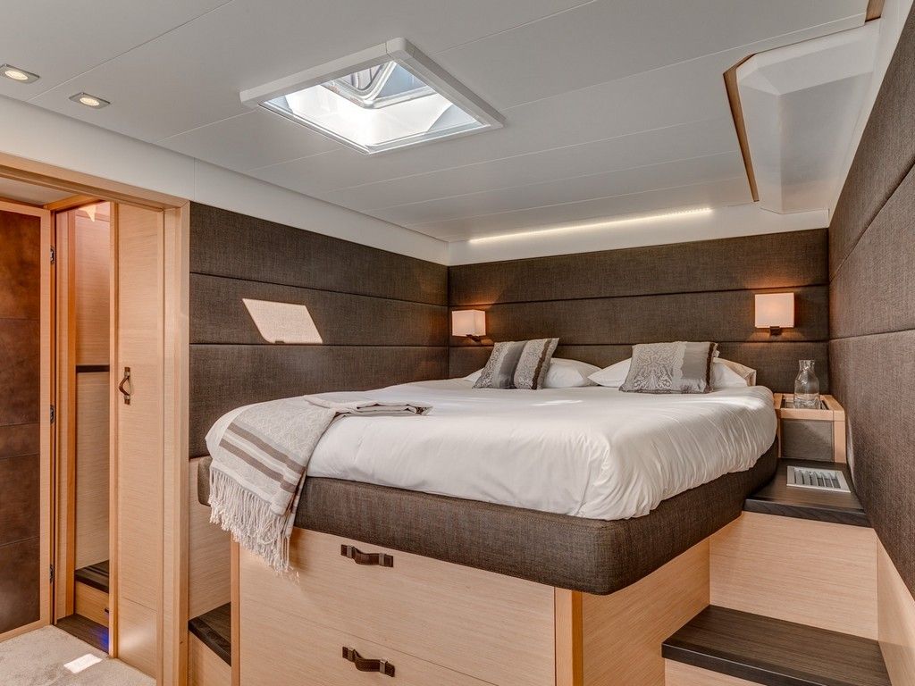 Une chambre à coucher moderne avec un puits de lumière, un lit avec une tête de lit, des tables de chevet et une armoire.