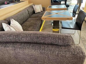 A modern living room with a sectional sofa, a glass-top coffee table, and black chairs.