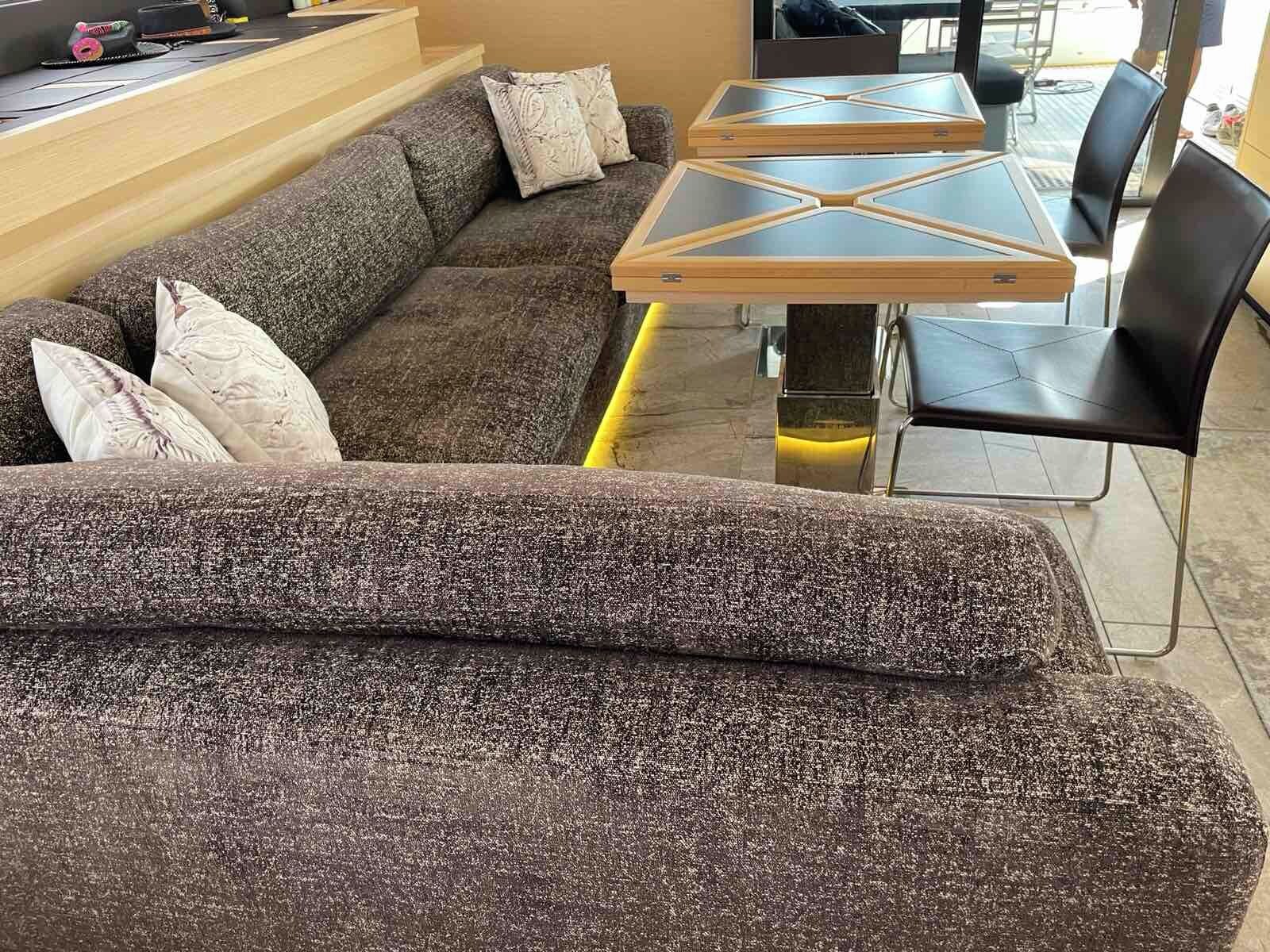Ein modernes Wohnzimmer mit einer Eckcouch, einem Glastisch und schwarzen Stühlen.