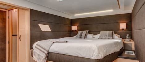 A modern bedroom with a skylight, a bed with a headboard, bedside tables, and a wardrobe.
