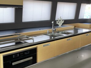 Une cuisine moderne dotée d’un évier en acier inoxydable, de meubles en bois et d’un lave-vaisselle encastré.
