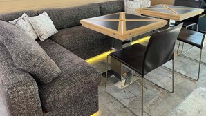 A modern lounge area with a grey sofa, two glass-top tables, and black chairs. - Sun-Kissed Sailing Adventure in Islas Cícladas, Mykonos (Mykonos)