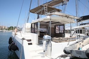 A sailboat with a covered deck area, a seating arrangement, and a visible engine.