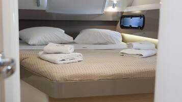 A neatly made bed with white linens and pillows, a small bedside table with a lamp, and a window with a view.