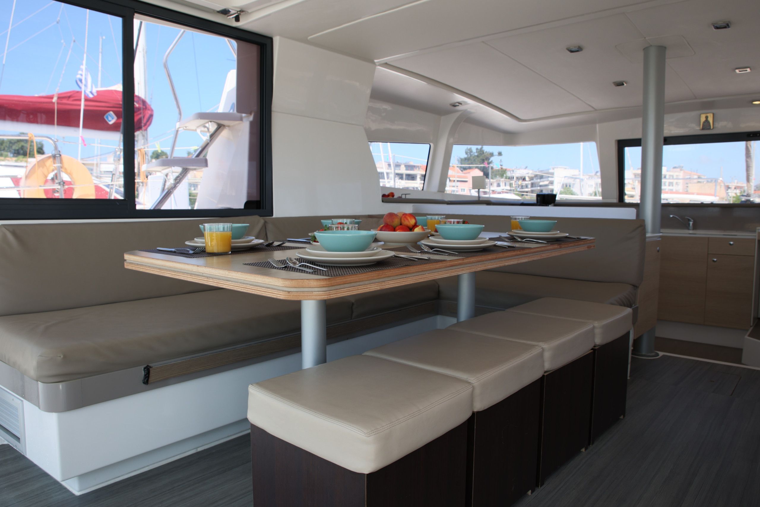 A boat interior with a dining area featuring a table set with plates, bowls, and cutlery.