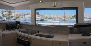 A compact galley kitchen with a sink, stove, and coffee maker.