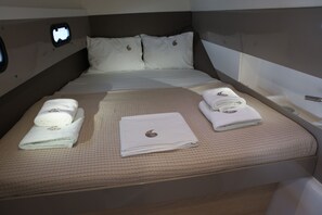 A neatly made bed with pillows, a headboard, and a window.