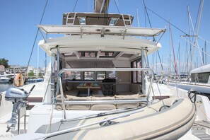 A yacht with a covered deck area, seating arrangements, and a visible engine.