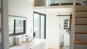 A modern interior with a loft bedroom, a kitchen, and a staircase.